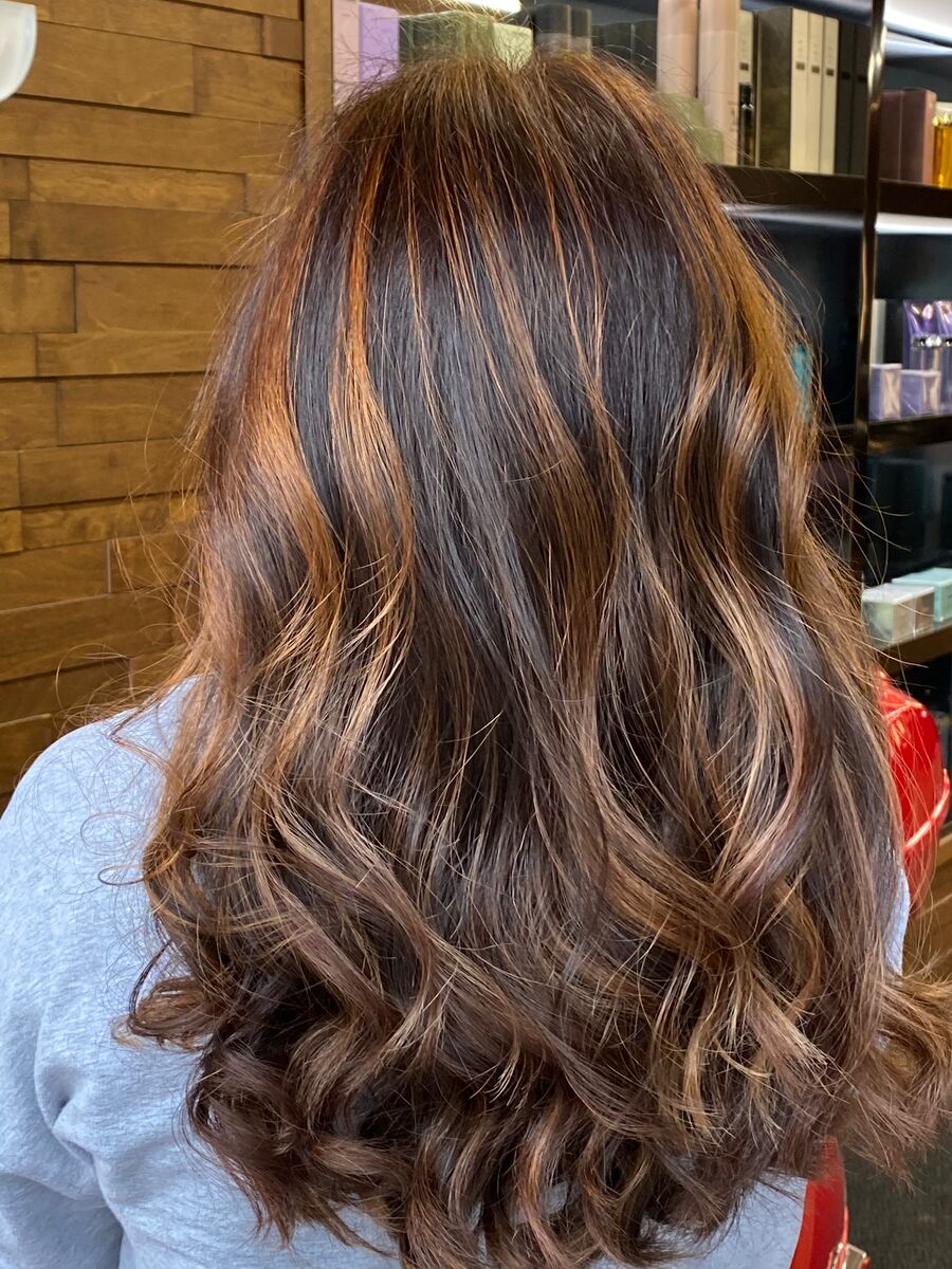 Chocolate brown hair with copper pieces, styled in long waves