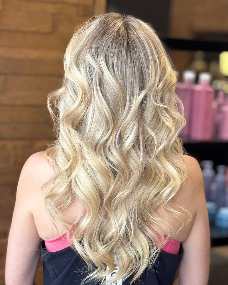 Long blonde hair styled in loose, bouncy waves, by Dea